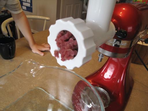 ground beef coming out of the grinder attached to the mixer