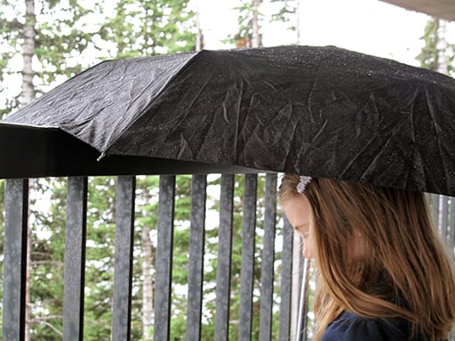 close up of a girl and black umbrella during the rain