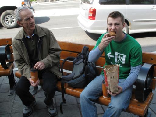 two men sitting at the bench enjoying the food and coffee from McDonalds