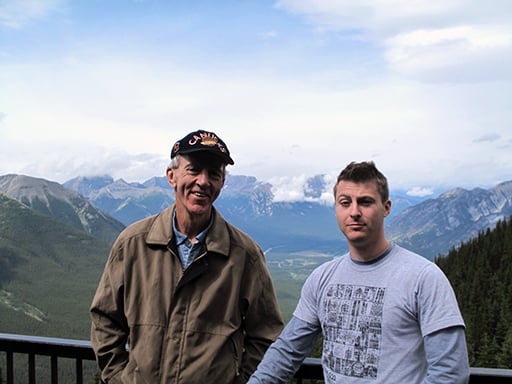two men standing near the rails with the mountain view on their back