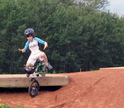 young boy riding a bike, wearing a blue helmet trying to fly