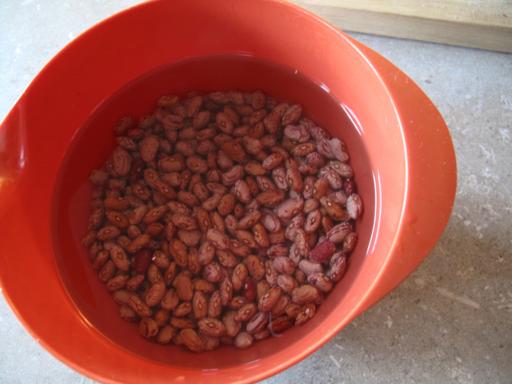 red bowl with beans submerged in water
