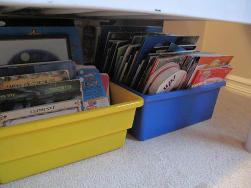 Tucked books in yellow and blue tray under the bed