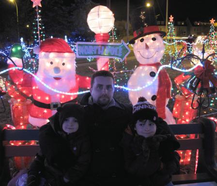 Dad with the kids sitting in the bench with lighted Santa and snowman 