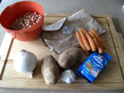 Pasulj ingredients in a wooden board with the beans soaked in a bowl of boiled then cooled water