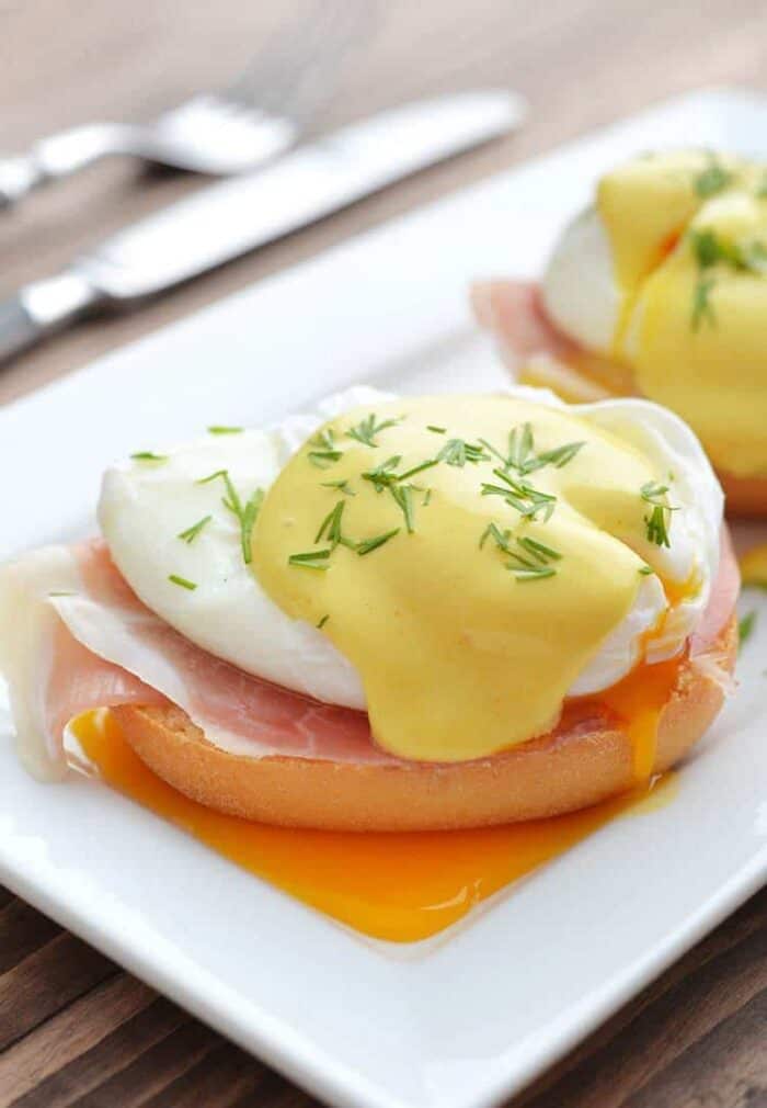 poached egg over buttered muffin with a slice of bacon topped with Hollandaise sauce