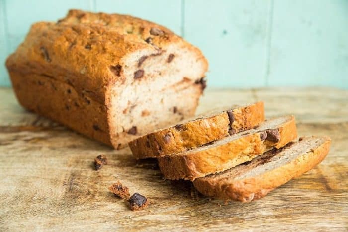 Banana Bread loaf and slices on wooden board and turquoise background
