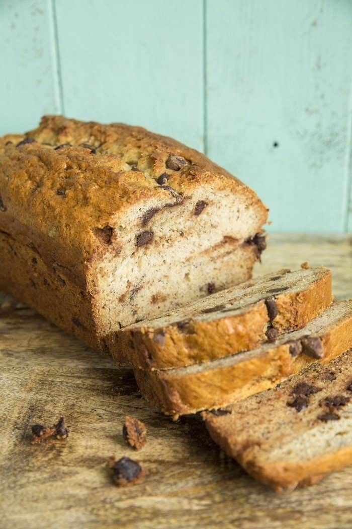 Banana Bread loaf and slices on wooden board and turquoise background