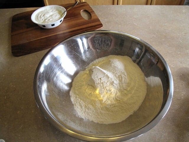 flour mixture for scones in a large stainless bowl, sour cream mixture in a small white bowl on the back