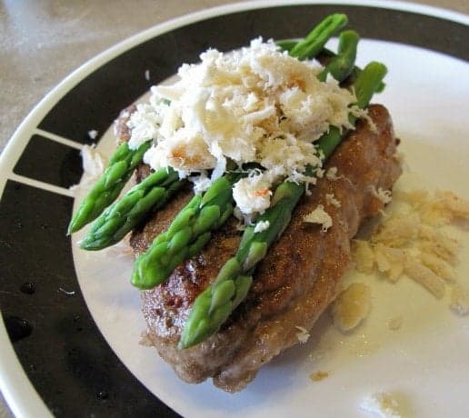adding the heated crab meat on top of Steak with asparagus