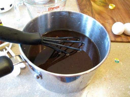 Mixing the brown sugar, soy,vinegar, water and ketchup in a pot using plastic whisk