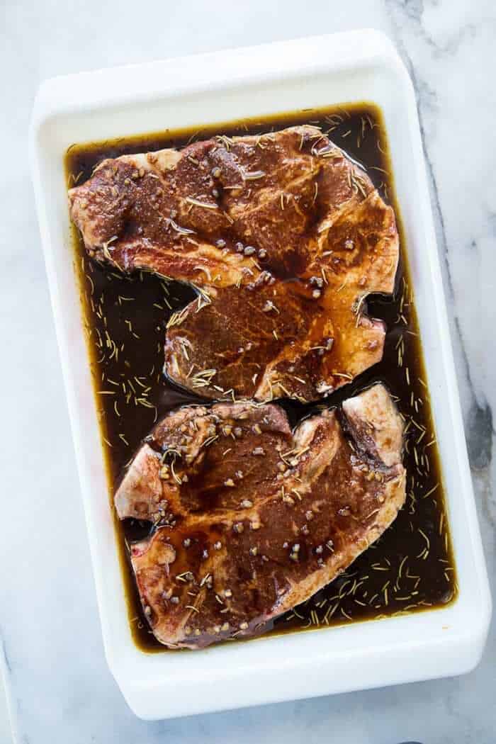 T-Bone steaks in the steak marinade in white pan