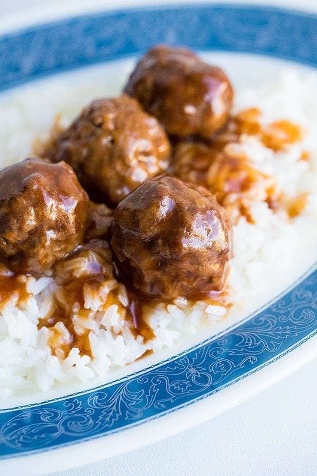 sweet and sour meatballs on white rice in a blue pattern plate