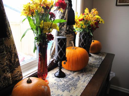 large pumpkins and flowers on the buffet table near the window