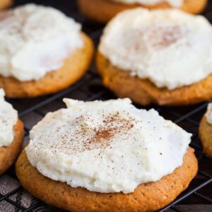 close up frosted pumpkin drop cakes with icing on cooling rack