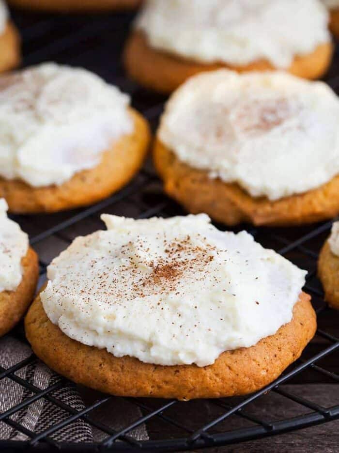 close up frosted pumpkin drop cakes with icing on cooling rack