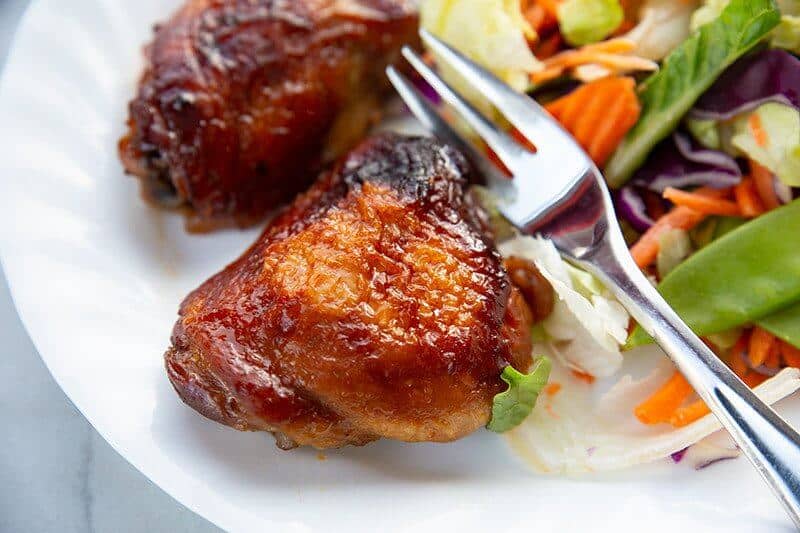 baked Teriyaki Chicken on a white plate with a fork and some vegetables