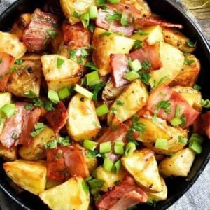 easy delicious skillet fried potatoes with bacon and green onions garnished with parsley placed on a light blue cloth on top of the table