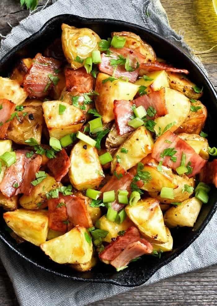 close up easy delicious skillet fried potatoes with bacon and green onions garnished with parsley placed on a light blue cloth on top of the table
