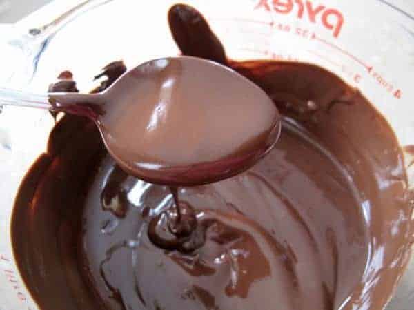 a spoon with Melted chocolate in a Pyrex glass
