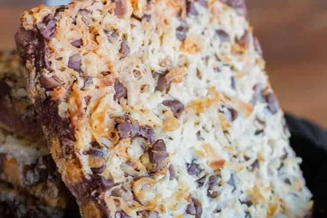 close up slice of Seven layer bars loaded with pecans, chocolate chips and shredded coconut