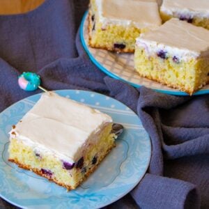 close up blue tablecloth underneath the plates of Lemon Blueberry Coffee Cake top with lemon butter cream icing