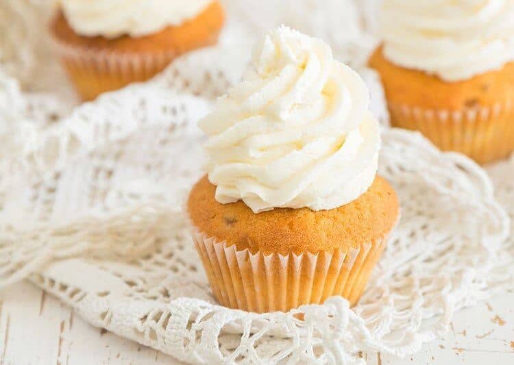 white crochet table runner underneath vanilla cupcakes with white buttercream icing on top