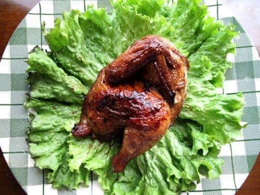Honeyed Cornish Game Hens in a green checkered plate garnish with some lettuce leaves