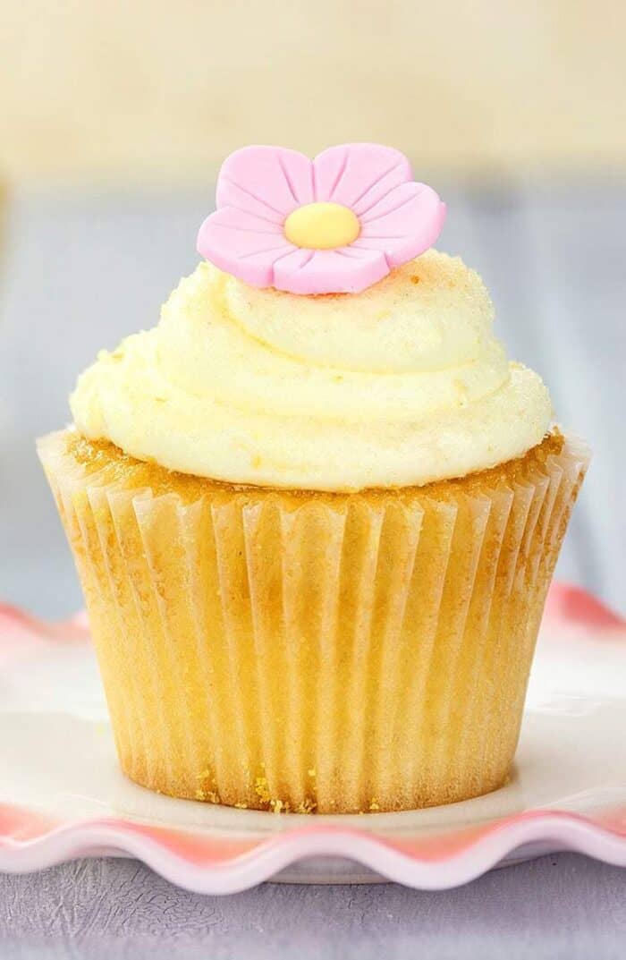Lemon Buttercream Frosting and pink icing flower on top of lemon cupcake