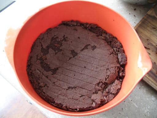 pressed caked in a red bowl with cherries and cream added, bottom of the cake on top of the mixture