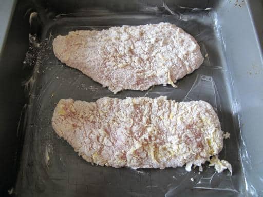 coated chickens placed in a baking pan ready to sit in the fridge