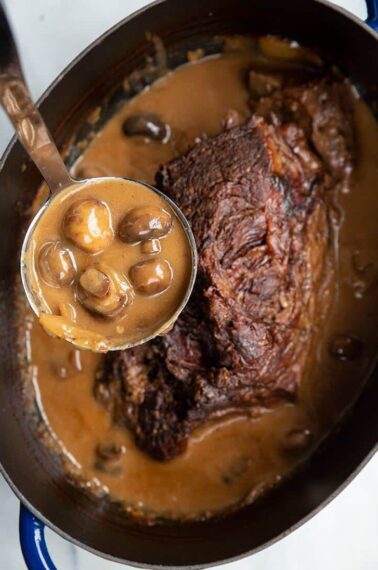 Creamy Mushrooms and Gravy in a Ladle from a slow cooker with Cooked Chuck Roast