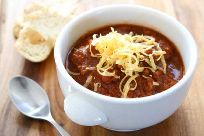 Kitchen Sink Crockpot Chili in a white bowl with grated cheese on top