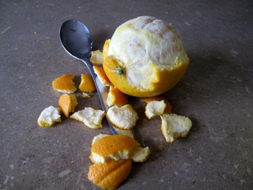 peeling the fresh orange using a spoon