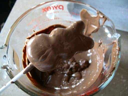 bunny peep on a stick coated with melted chocolate in a Pyrex measuring cup