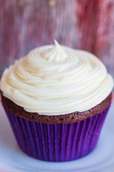 close up Cream Cheese Icing swirled on a cupcake with blue cupcake liner