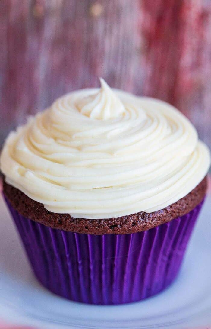 close up Cream Cheese Icing swirled on a cupcake with blue cupcake liner