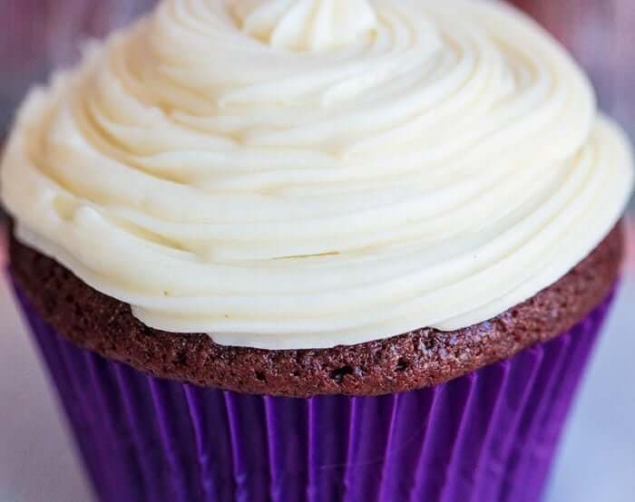 close up Cream Cheese Icing swirled on a cupcake with blue cupcake liner