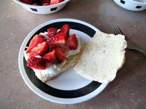 sliced scone with whipped cream and topped with sliced strawberries
