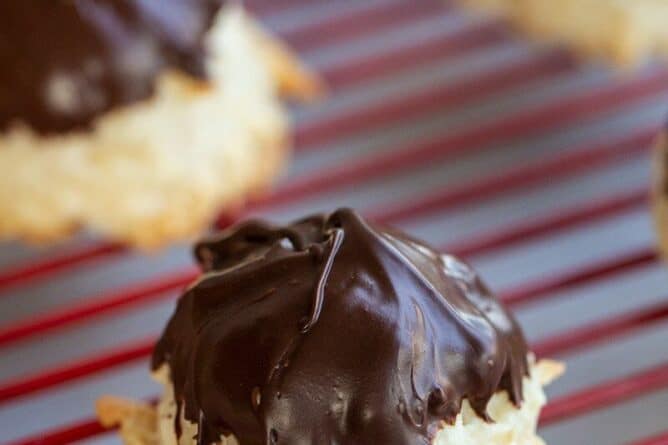 close up Chocolate Dipped Coconut Macaroons on red cooling rack