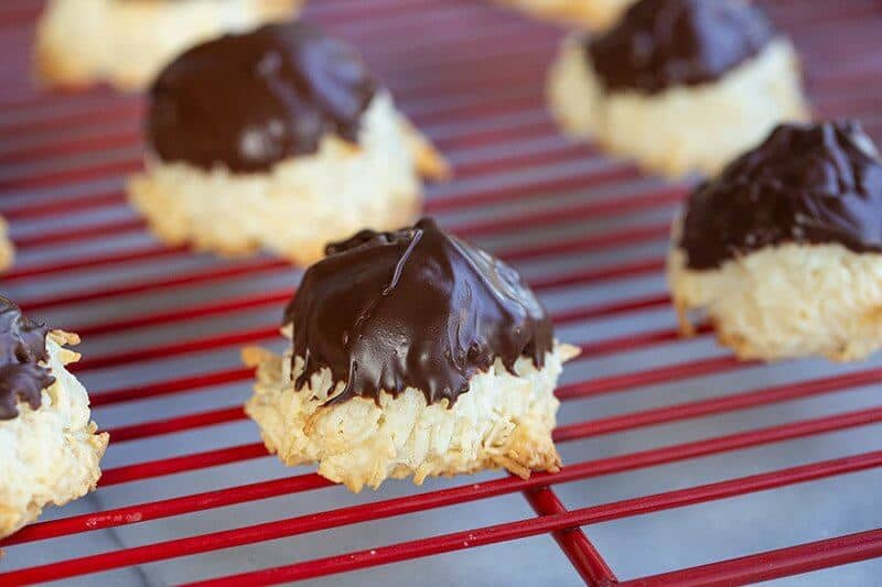 Coconut Macaroons in a red cooling rack with melted chocolate on top
