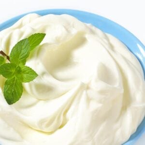 Lemon Whipped Cream in Pyrex blue bowl garnish with small fresh leaves