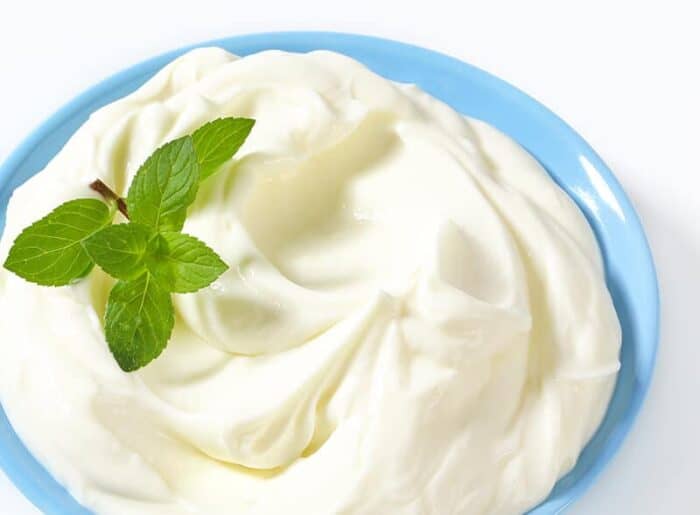 Lemon Whipped Cream in Pyrex blue bowl garnish with small fresh leaves