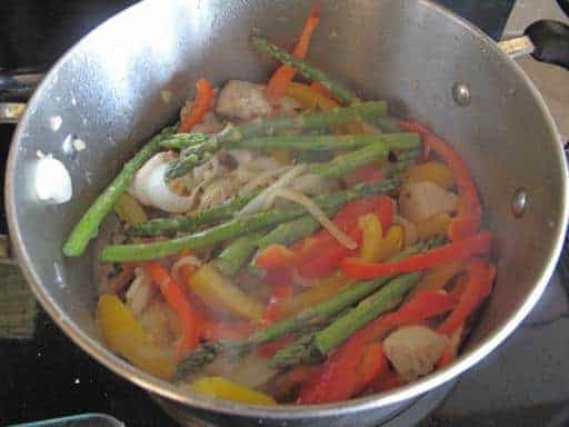 Adding in the sauce to the pot with chicken and vegetables