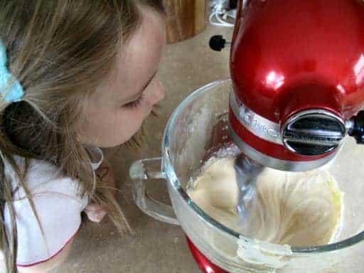 a little girl enjoying the smell of mixture with eggs and vanilla added on it