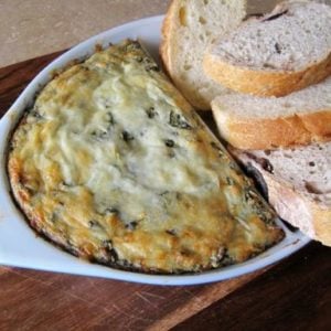 Hot N' Cheesy Spinach & Artichoke Dip with slices of bread on the side