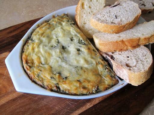 Close up Hot N' Cheesy Spinach & Artichoke Dip with slices of bread on the side