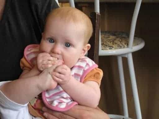 little baby holding her foot with two hands and trying to chew it