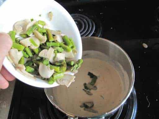adding the fried mushrooms and asparagus to the sauce in a separate pot