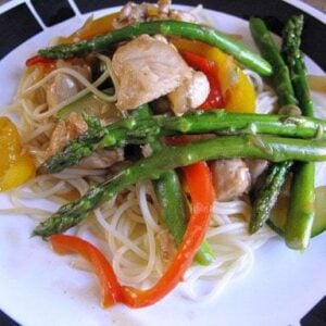 A Plate with Chicken Asparagus Stir Fry Over Angel Hair Pasta